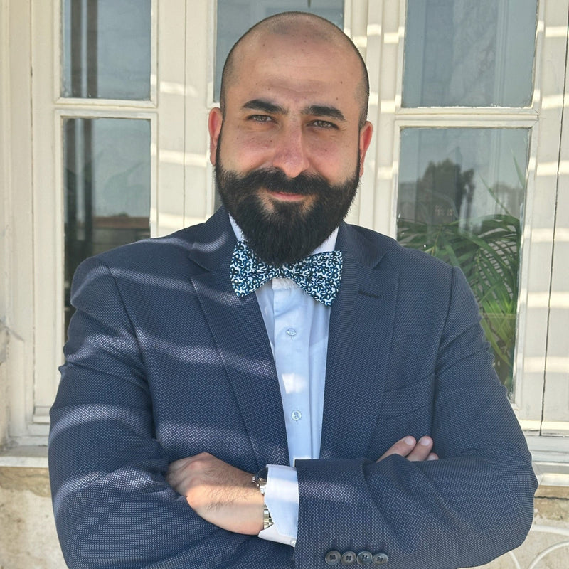 Man in a suit with a bow tie standing in front of a building